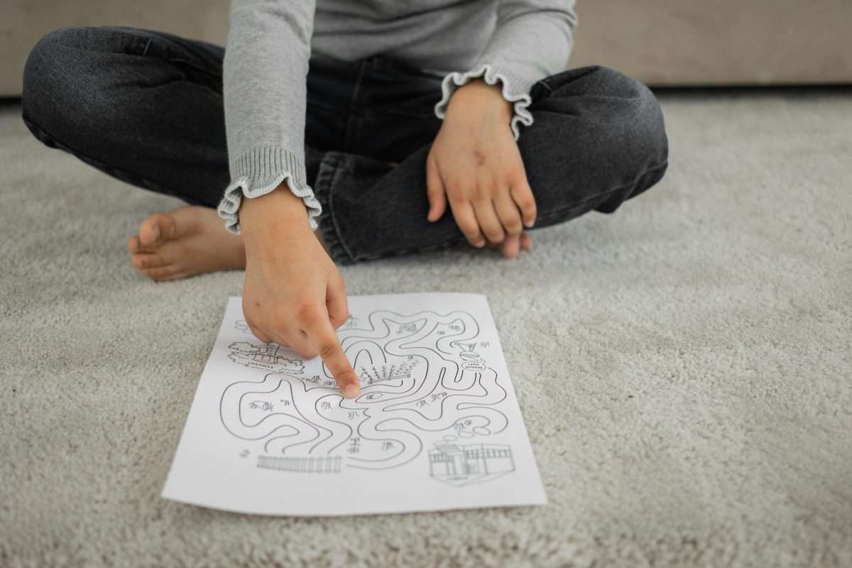 Contextual Safeguarding: Relationships characterised through CARE - image of a child cross-legged pointing at a maze puzzle
